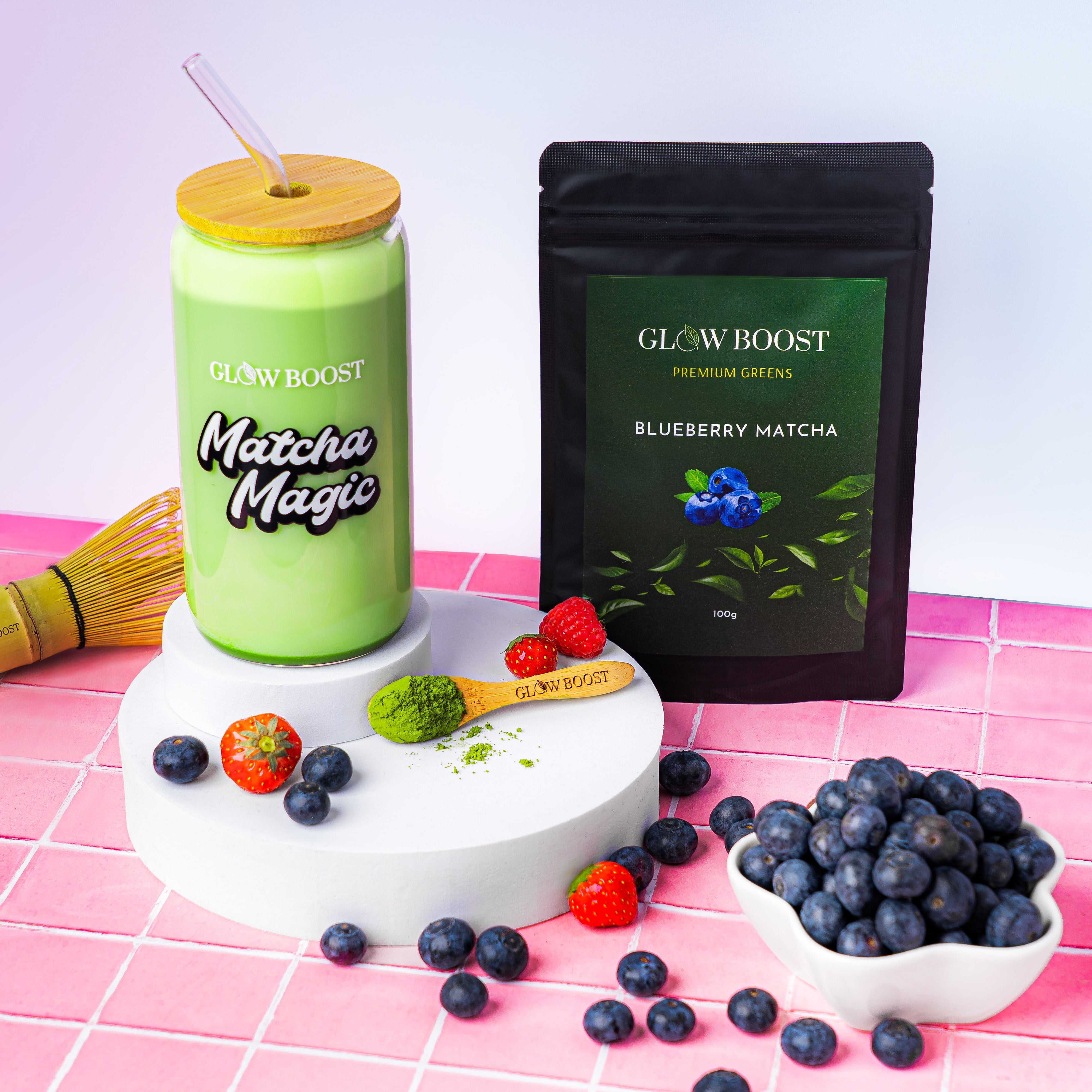 Matcha Magic drink with a straw, blueberries, and a Glowboost package on a pink grid background